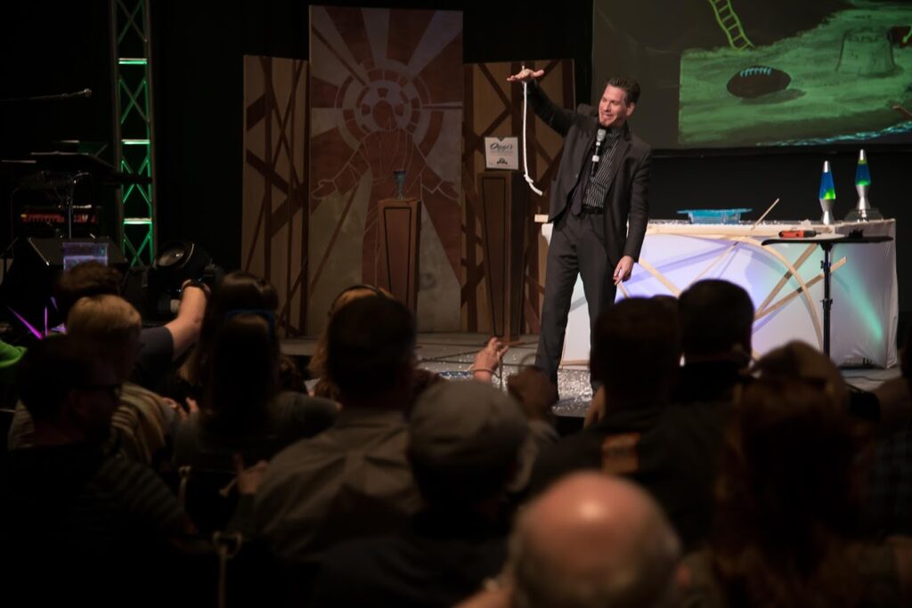 Comedy magician Zach Waldman performing rope trick on stage at corporate event